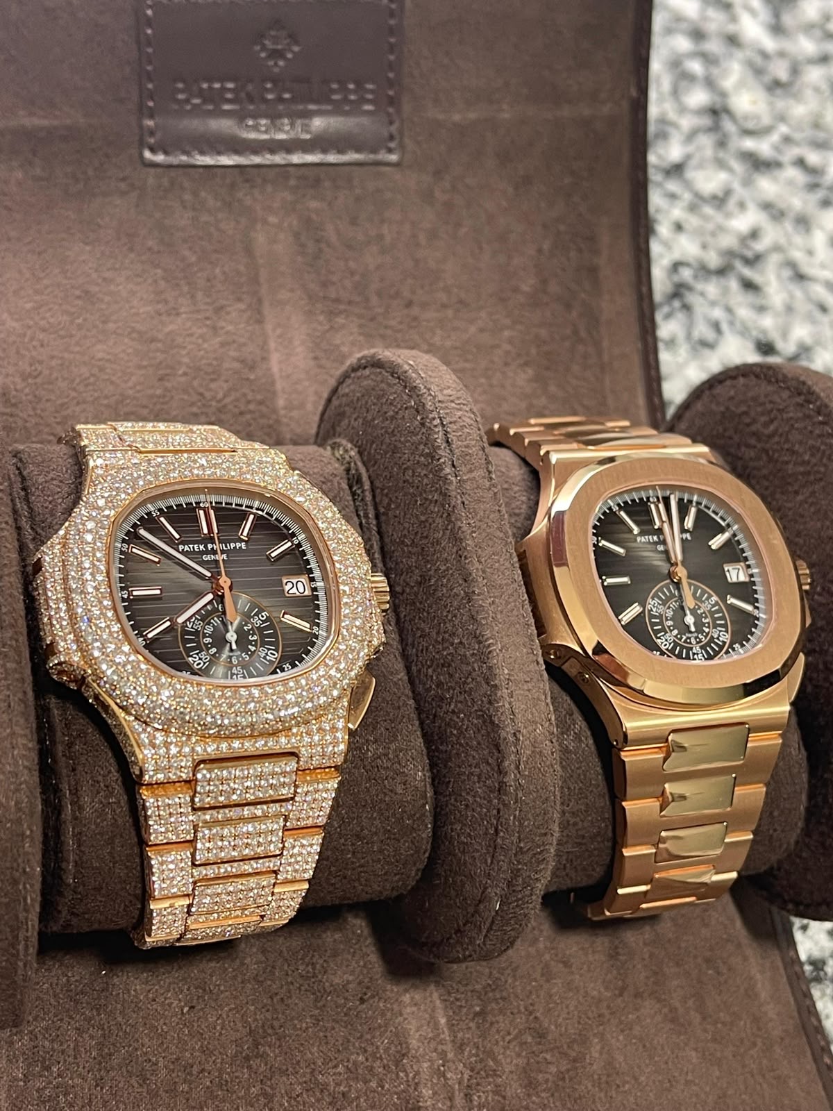 Zwei goldene Luxusuhren, eine diamantbesetzt, auf dunklen Uhrenkissen